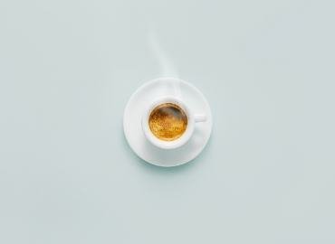 A cup of coffee on a pale table, seen from above