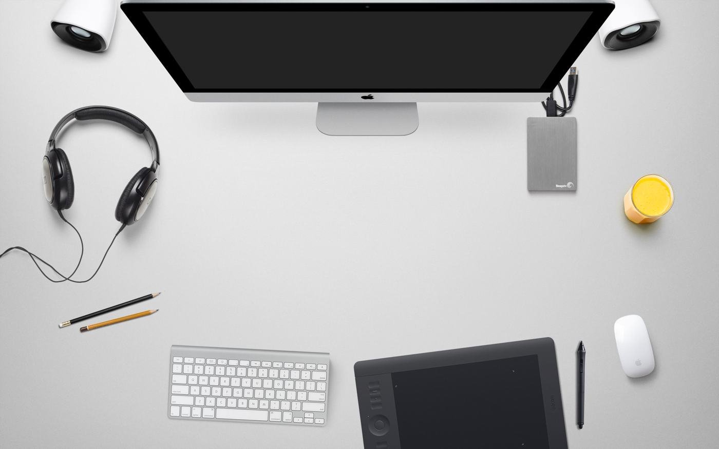 A tidy white desk with a monitor, keyboard and headphones