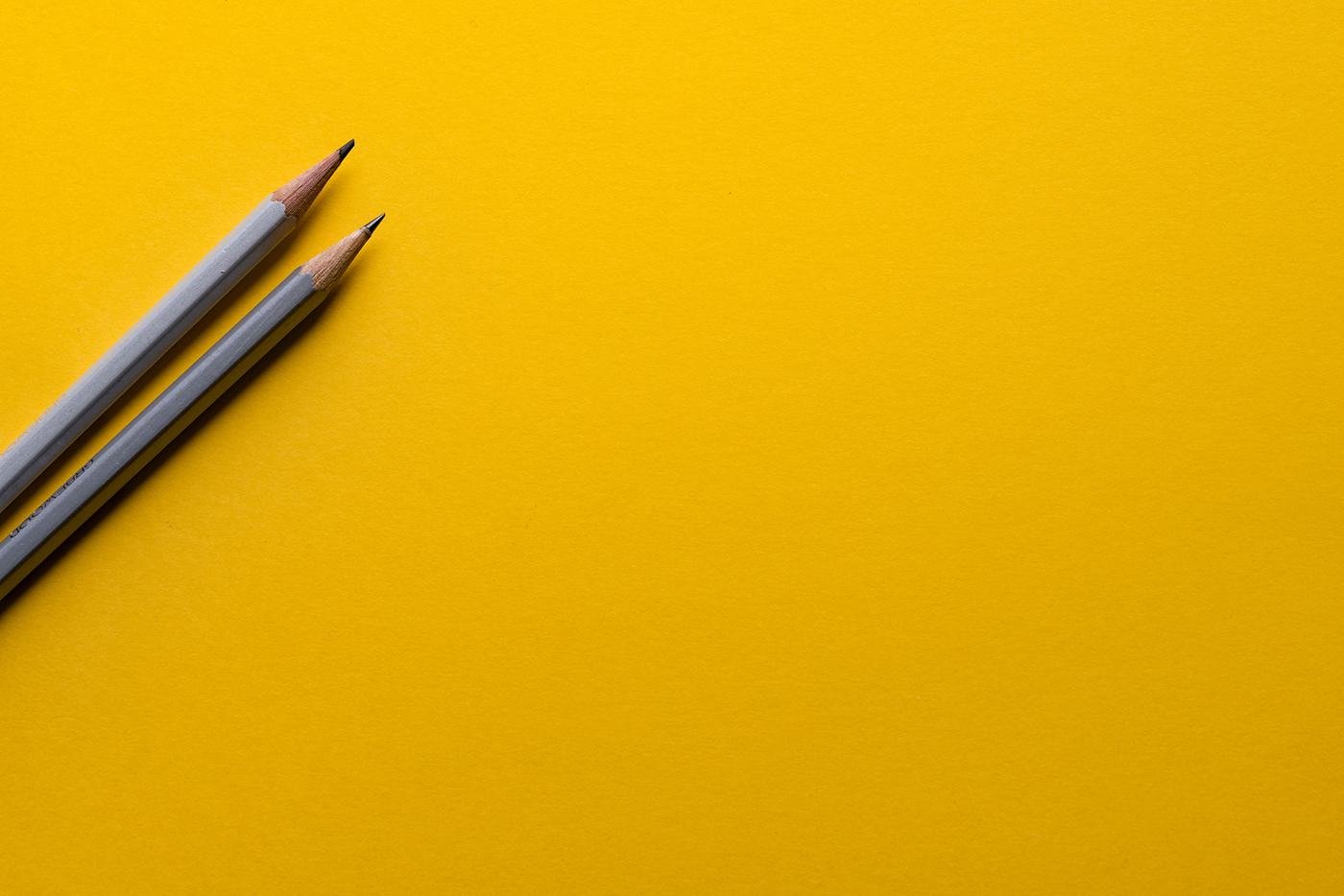 Pencils and paper on a bright yellow desk